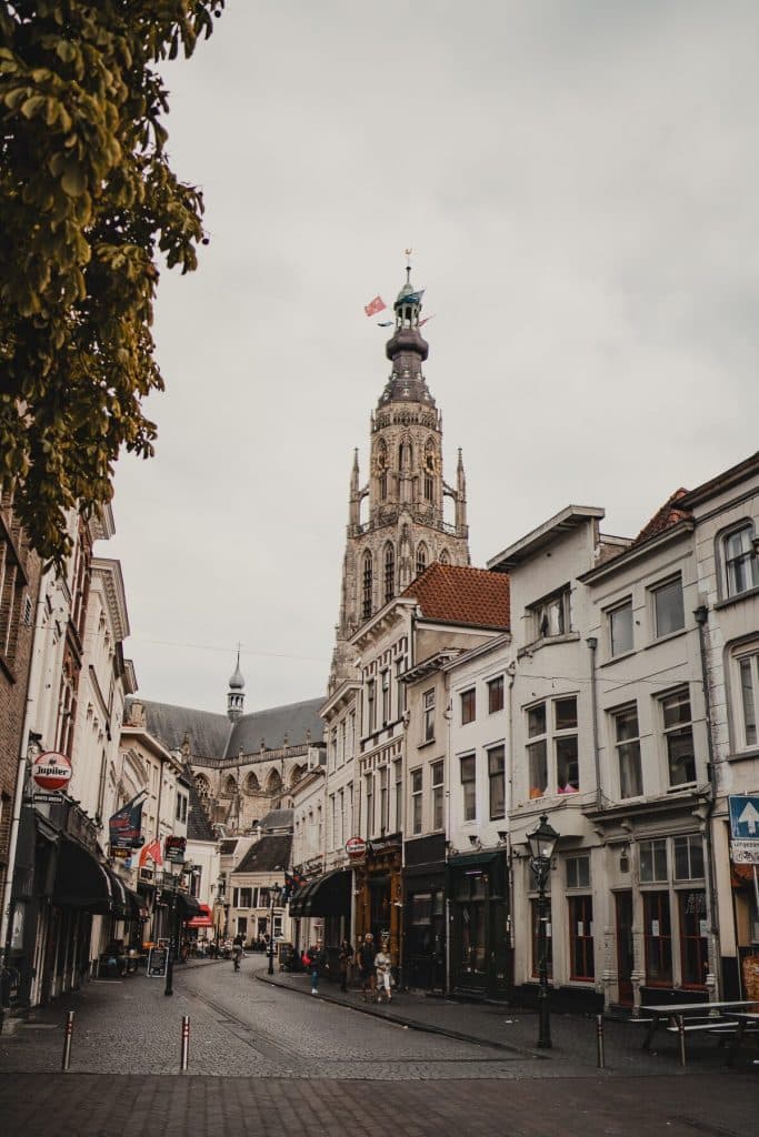 Een hoge kerktoren torent uit boven de historische witte gebouwen langs een geplaveide straat vol winkels en cafés, en biedt onder de bewolkte hemel een glimp van het goede leven.