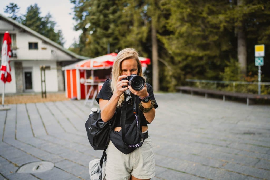 Een vrouw met een camera fotografeert op het plein bij het bergstation van Cardada, boven Locarno.