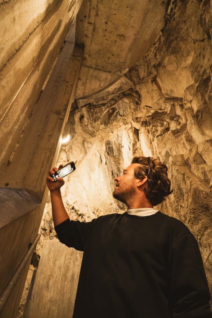 Een man houdt zijn gsm omhoog in de ruwe gang die door de rots naar Castelgrande in Bellinzona leidt.