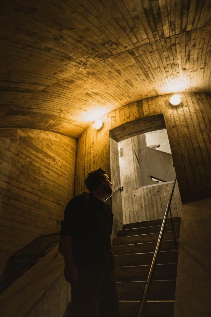 Een man loopt in een betonnen gang met trappen en lampen naar boven, in de toegang van Castelgrande in Bellinzona.