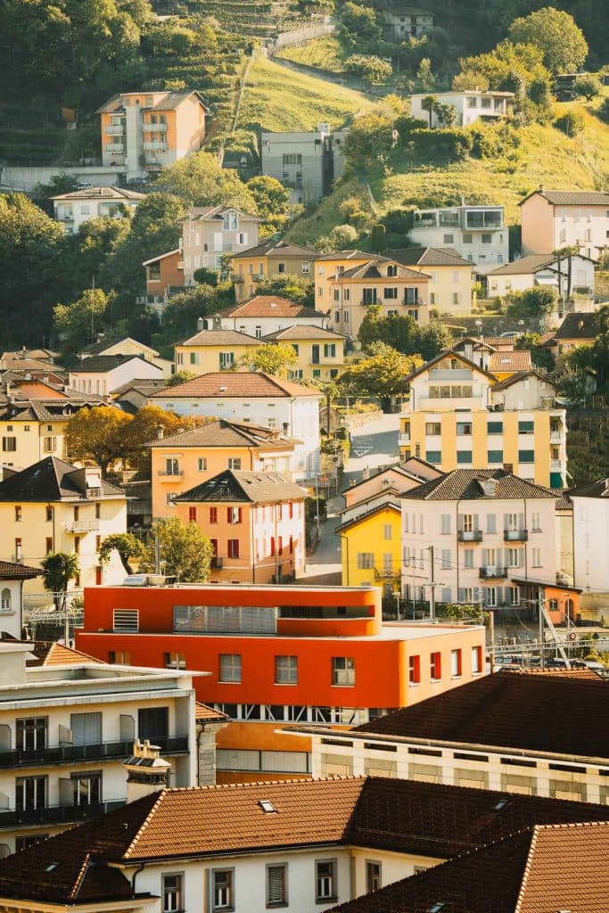 Gele, roze en oranje huizen tegen de helling van Bellinzona, gezien vanaf Castelgrande.